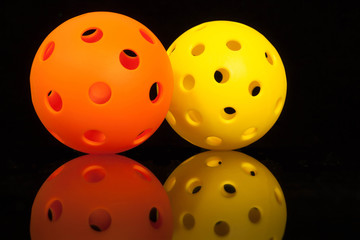 Mirrored Pickleballs...Orange & Yellow Pickleballs on a Black background with mirror reflection.