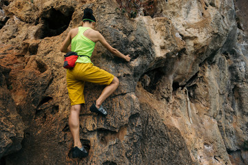 female rock climber climbing on steep cliff