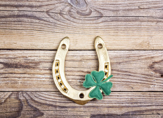 Golden horseshoe and clover leafon old wooden boards. St.Patrick's day holiday symbol.