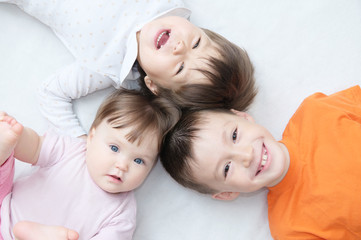 happy kids, three laughing children different ages lying, portrait of boy, little girl and baby...