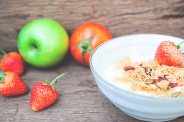 Greek yogurt with granola in ceramic bowl, apple, strawberries and tomato in background, Healthy food, Super food