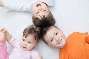 happy kids, three laughing children different ages lying, portrait of boy, little girl and baby girl, happiness in childhood of siblings, living in big family with three children