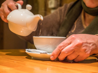 Closeup view tea pot pouring drink into cup in senior hands