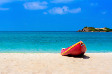 Red boat on the beach with blue sea and blue sky background