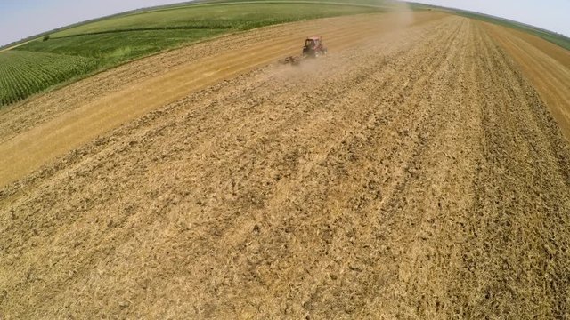 Tractor pulling land cultivating machine. Aerial footage.