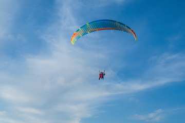 Paragliders in bright blue sky, tandem of instructor and beginner