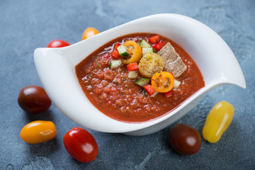 White bowl with spanish cold soup gazpacho on a blue stone background, horizontal shot