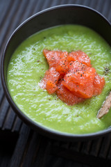 Close-up of cream-soup with green peas and addition of salmon fillet, vertical shot, selective focus