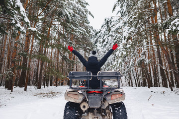 Naklejka premium young girl on a motorcycle rides in snow-covered pine forest in winter