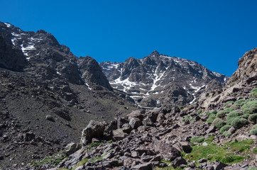 Toubkal national park in springtime with mount, cover by snow and ice, valley near Refuge Toubkal, start point for hike to Jebel Toubkal, – highest peak of Atlas mountains and Morocco