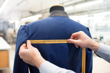 Tailor doing jacket measurement in workshop