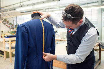Tailor measuring the length of a jacket
