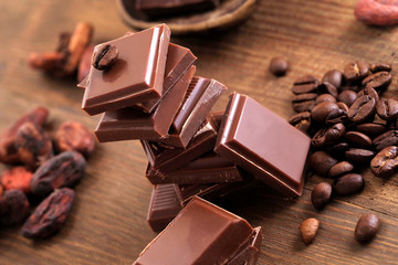 Broken dark chocolate, cocoa powder and coffee beans on a wooden table