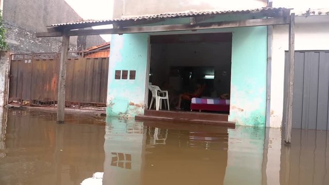 A family sits in their home surrounded by flood water