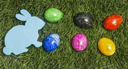Fototapeta na wymiar six colourful eggs and card bunny lay on green grass.