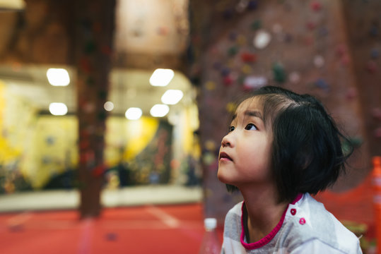 Girl observing activity at indoor rock climbing gym