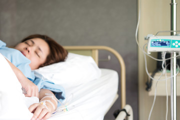 Selective focus woman patient's lying on hopital bed with hand receiving saline solution.