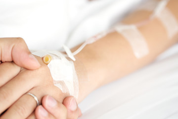 Man hand holding woman patient's hand on bed in hospital for reassuring and encouragement.