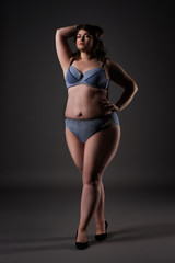 Plus size sexy model in underwear, fat woman on gray background, overweight female body