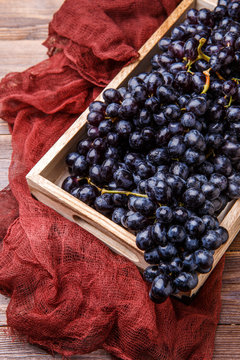 Photo of black grapes in wooden box with claret cloth