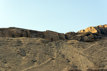 Sand dune and sandstone of the Sahara desert, near Cairo in Egypt with ruins of the entrance of an Egyptian tomb carved into the mountain