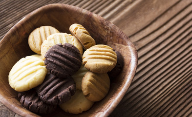 Chocolate cookies in a wooden bowl on brown wooden background