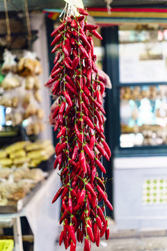 Close-up of bunch of very red colored chilli peppers with an unfocused background of food stalls located in the market called Do Bolhao in Porto, Portugal