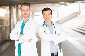 Fototapeta premium medical doctor professional team talked consult. Two young doctor Caucasian and Asian standing in hospital holding laptop and folder city building background.