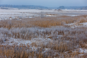 Winter morning, snowy surroundings, cold, frosty. Little river with ice. In some places, the river is not frozen. Winter landscape in the countryside with a small river.