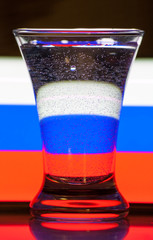 A glass of vodka with light in the background. Small bubbles