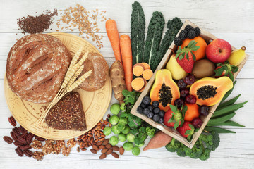 High fibre healthy food concept with wholegrain bread and rolls, nuts, seeds, fruit, vegetables and...