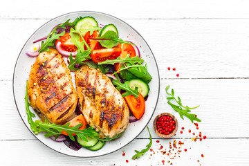 Grilled chicken breast. Fried chicken fillet and fresh vegetable salad of tomatoes, cucumbers and...