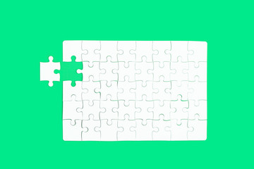 White jigsaw of puzzle on green background.