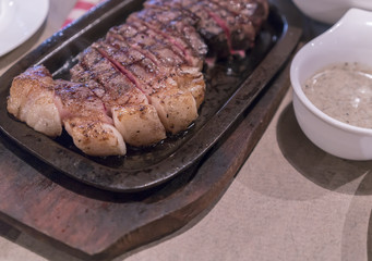 Big portion of delicious grilled tenderloin steak with truffle gravy serving on hot plate