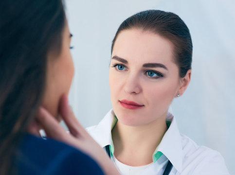 Young Concentrated Female Doctor Palpating Lymph Nodes Of A Patient. Doctor Touching The Throat Of A Patient.