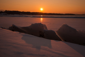Frozen lake with icebergs at sunset
