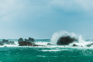 Fototapeta na wymiar Wild waves crashing on rocks in the sea at Tsumekizaki Park near Shimoda, izu peninsula, Japan