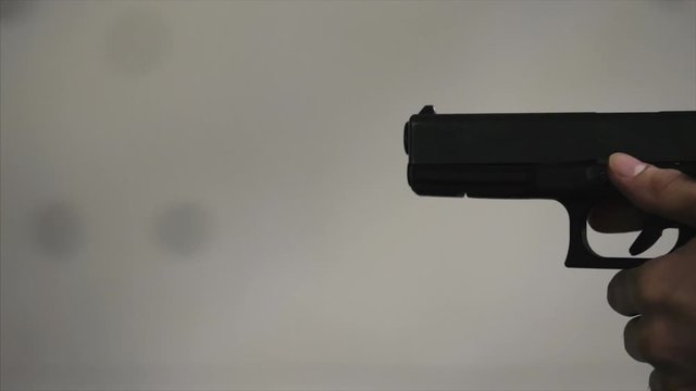 Gun is shot close-up. Pistol in hand close-up. Pistol being shot 1 times. Man shoots a black gun