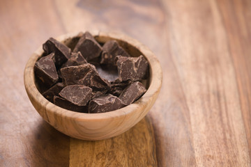 dark chocolate chunks in wood bowl on table