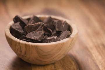 dark chocolate chunks in wood bowl on table