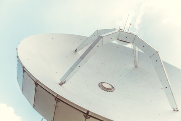 Big parabolic antenna with clear blue sky on background