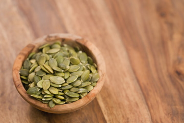green pumkin seeds in bowl on wooden table