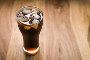 cola with ice in glass on wood table