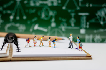 Miniature people : children with school bag standing on book with teacher and school background. Children back to school concept