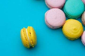 Flat lay colorful French pastel macaroons on blue background.