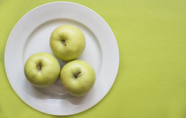 Close-up of green apple on white plate.