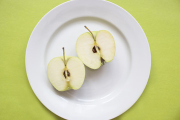 Close-up of green apple slice on white plate.