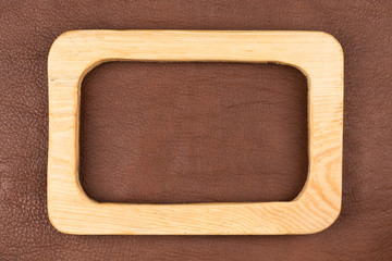 Rectangular board of light wood lies on brown natural leather. Texture of a tree.