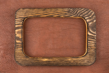 Rectangular board of dark wood lies on brown natural leather. Texture of a tree.