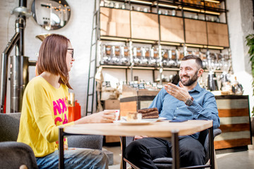 Couple of friends dressed casually having a conversation during the coffee break in the beautiful cafe